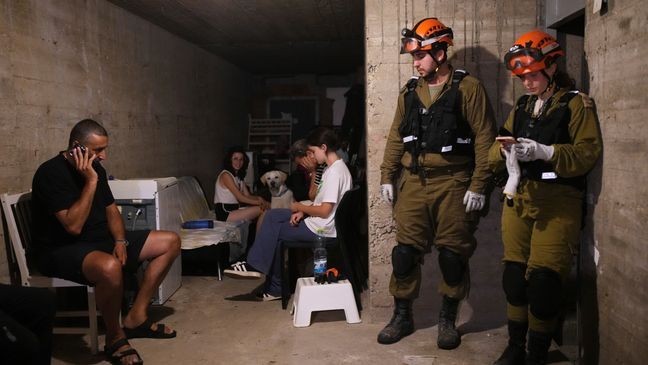 Israeli residents and security forces stay in a shelter of a residential area that was hit by a missile fired from Iran, in the central Israeli city of Bat Yam, early Sunday, June 15, 2025. (AP Photo/Ohad Zwigenberg)